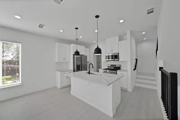 a kitchen with stainless steel appliances granite countertop a sink and a stove top oven with wooden floor