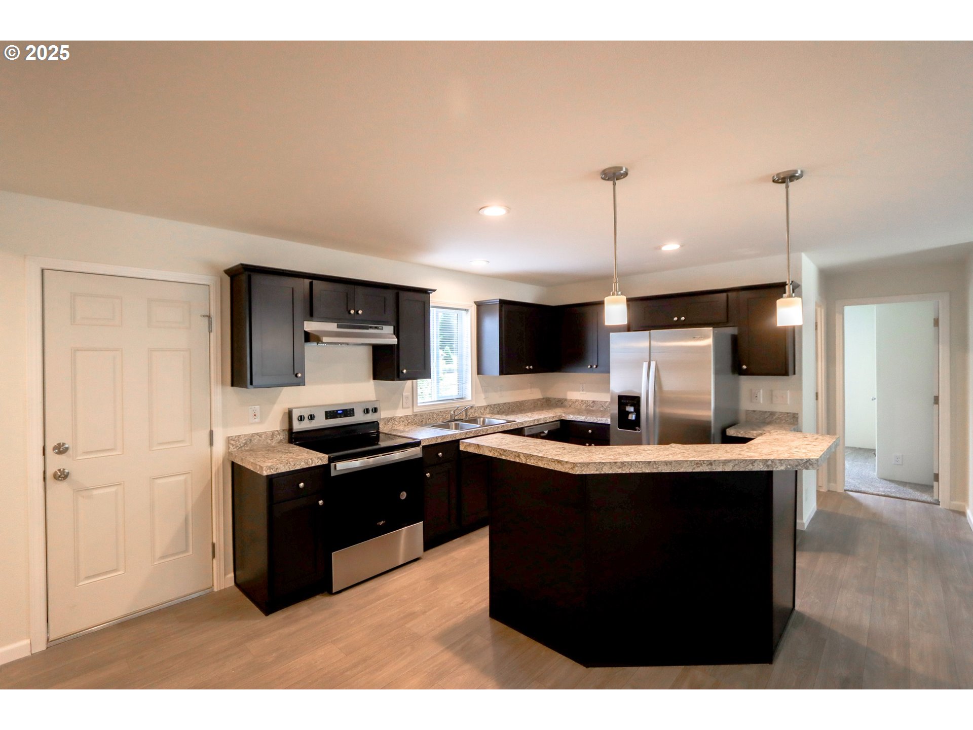 425 Providence Drive Reedsport, OR 97467 - Photo 6 of 33 a kitchen with stainless steel appliances kitchen island a sink dishwasher a stove and a refrigerator with wooden floor