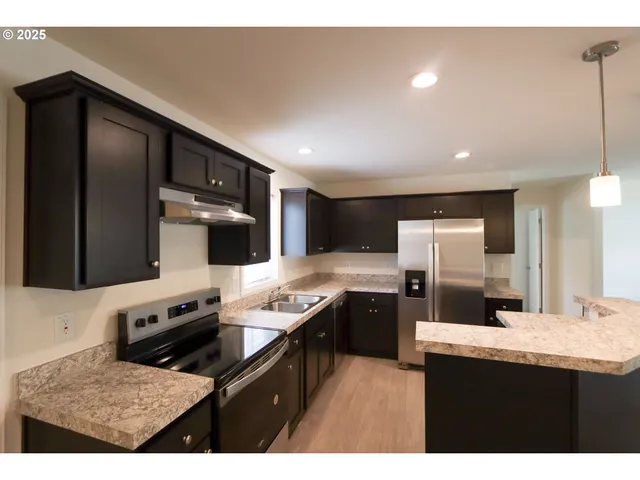 a kitchen with stainless steel appliances kitchen island granite countertop a refrigerator and a stove top oven