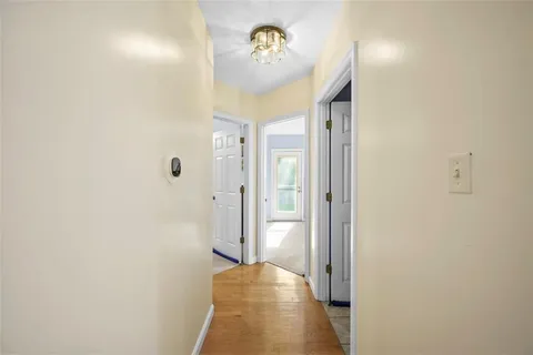 a view of a hallway with wooden floor and a bathroom