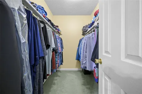 a view of walk in closet with clothes and shoes