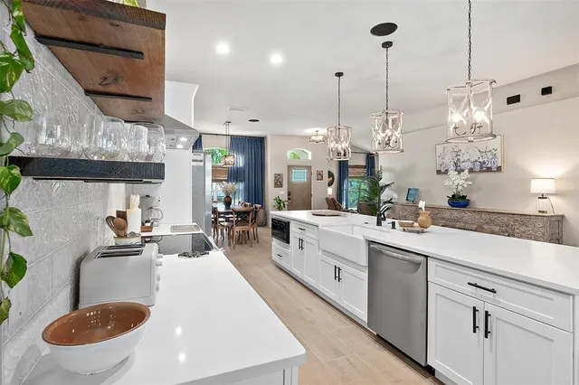 a kitchen with stainless steel appliances kitchen island granite countertop a table chairs and a chandelier