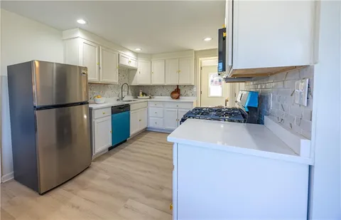 a kitchen with a refrigerator a stove a sink cabinets and a wooden floor