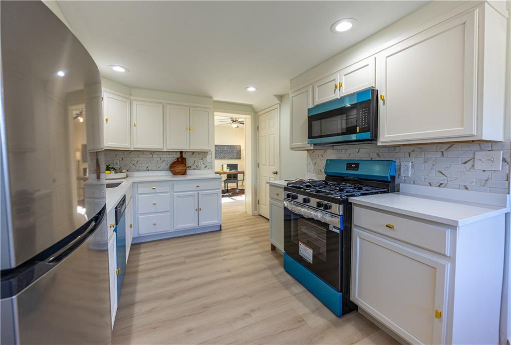 117 Oak Avenue Penn Hills, PA 15235 - Photo 10 of 26 a kitchen with stainless steel appliances a stove top oven a sink a refrigerator white cabinets and wooden floor