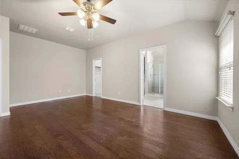 an empty room with wooden floor chandelier fan and windows