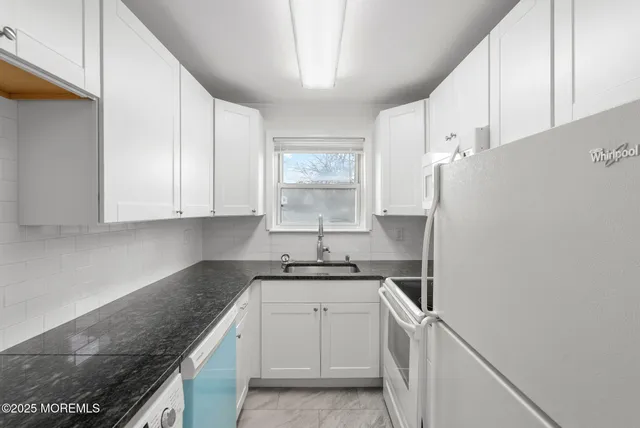 a kitchen with granite countertop white cabinets and white appliances