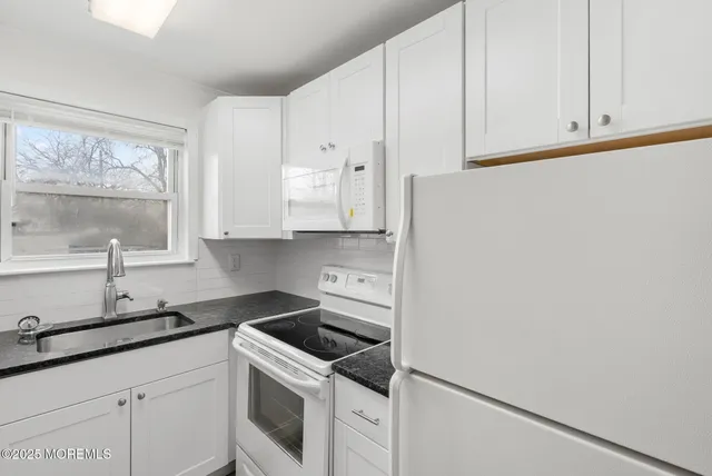 a kitchen with granite countertop a sink stove and cabinets