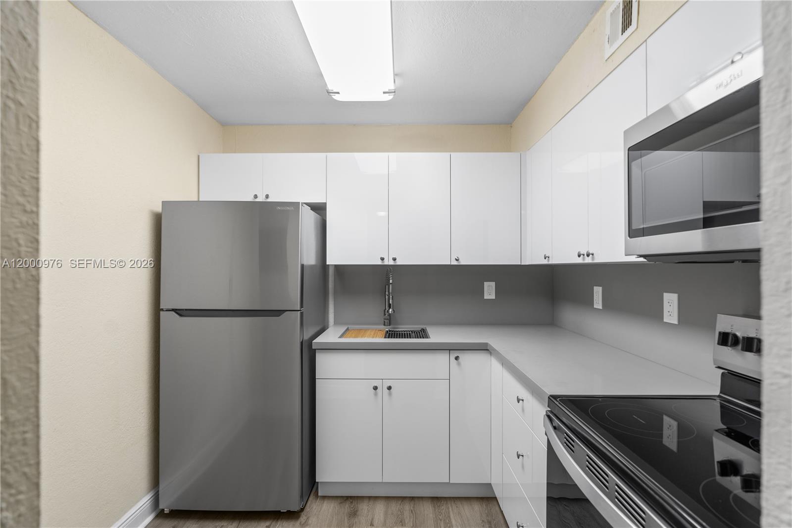 9441 Southwest 76th Street, Unit V32 Miami, FL 33173 - Photo 2 of 28 a kitchen with a refrigerator sink and cabinets
