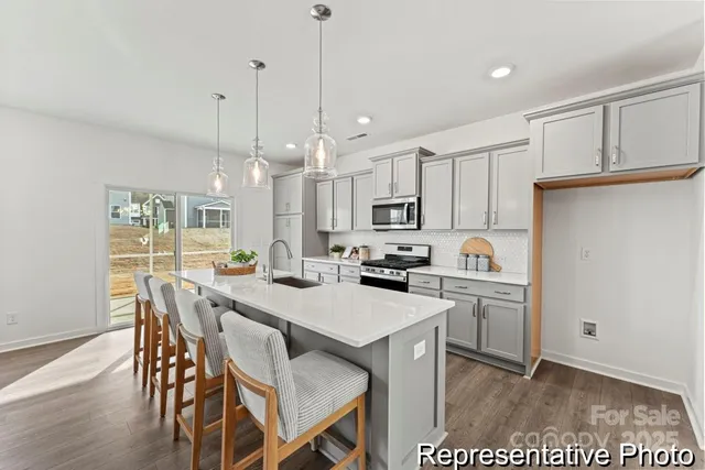 a kitchen with stainless steel appliances a stove a sink a dining table and chairs