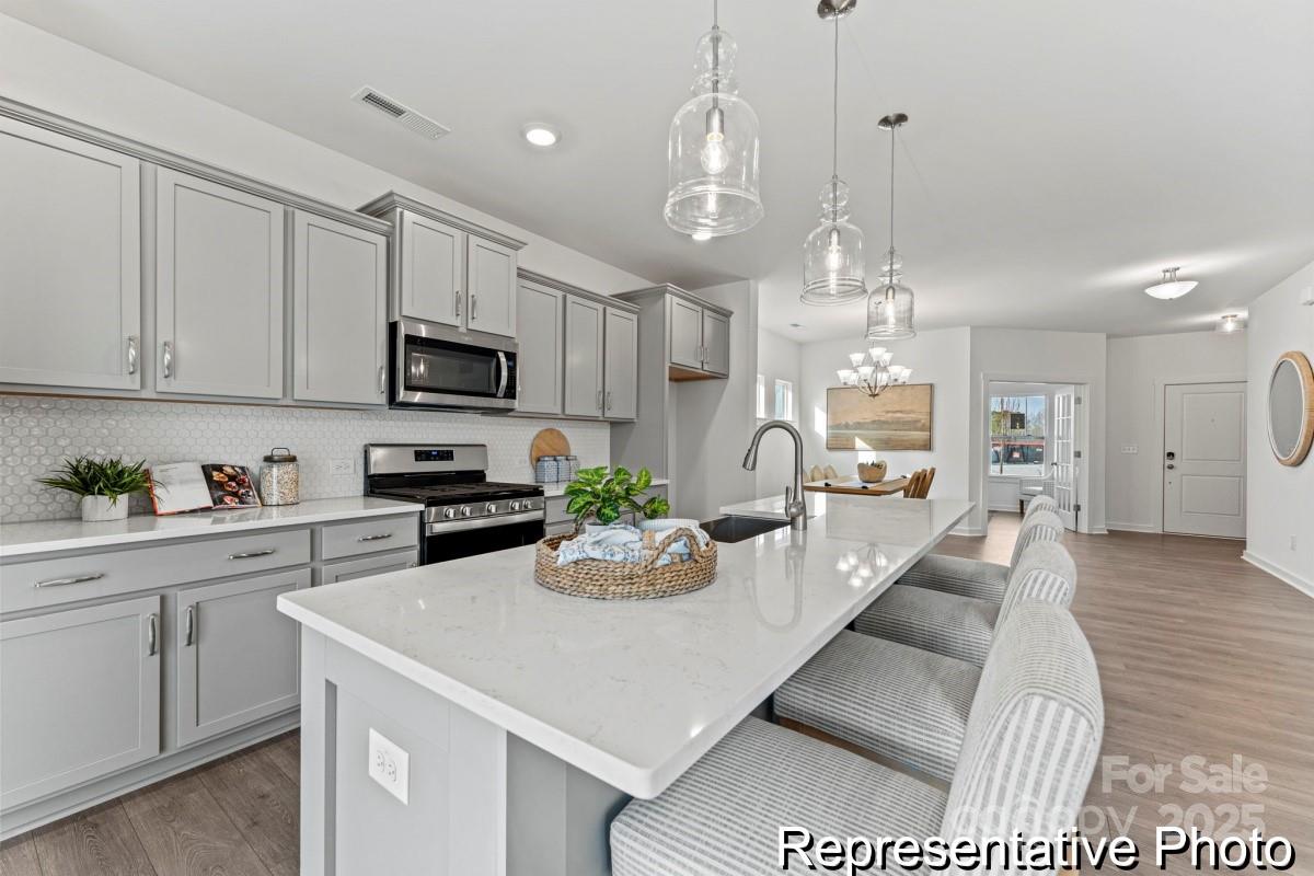 111 West Rice Planters Way, Unit 2P Statesville, NC 28625 - Photo 3 of 19 a kitchen with stainless steel appliances kitchen island granite countertop a refrigerator a stove a sink dishwasher and white cabinets with wooden floor