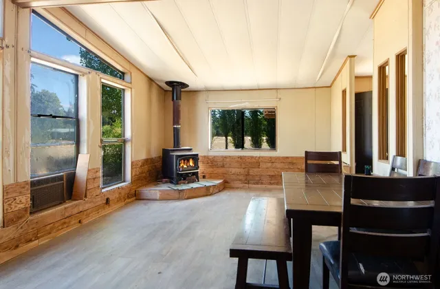 a dining room with wooden floor and large windows