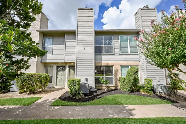a front view of a house with a yard and potted plants