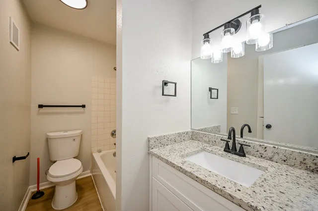 a bathroom with a granite countertop sink a toilet and a mirror