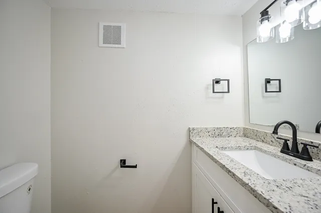 a bathroom with a granite countertop sink and a mirror