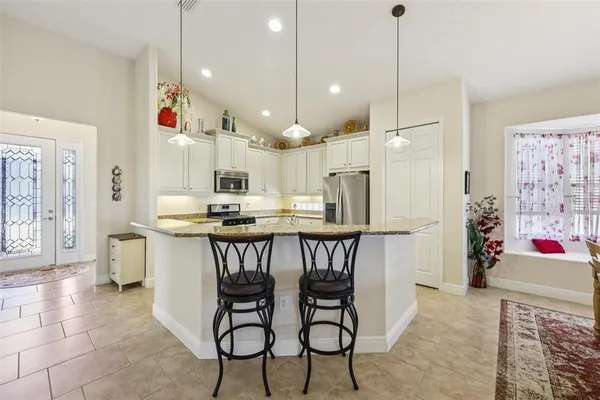 a kitchen with stainless steel appliances kitchen island granite countertop a table chairs and a refrigerator