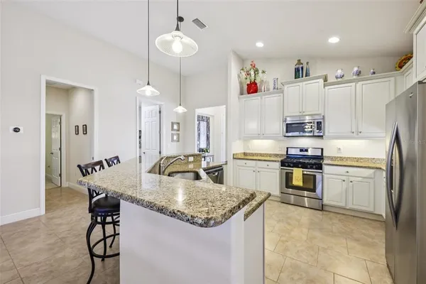 a kitchen with kitchen island granite countertop appliances cabinets a sink and a counter top space