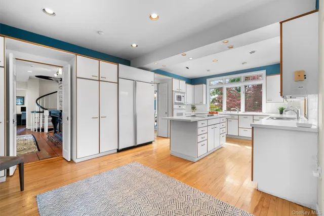 a large white kitchen with a large window and stainless steel appliances