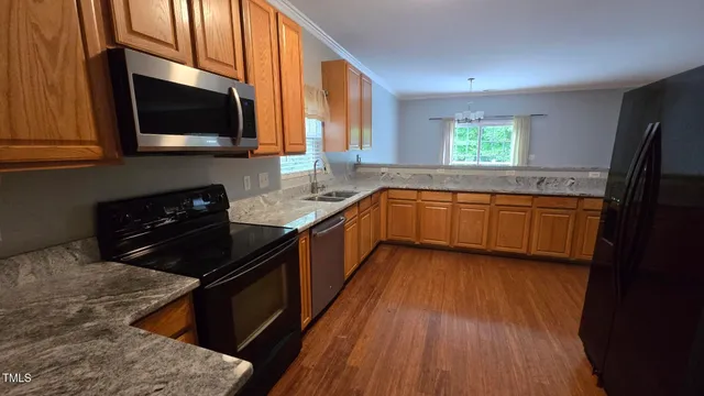 a kitchen with stainless steel appliances granite countertop wooden cabinets a stove a sink and a microwave