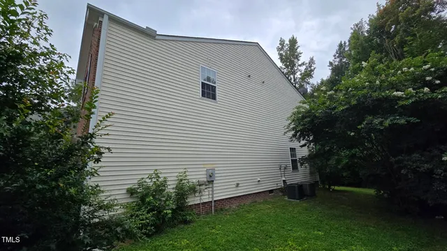 a view of a white house with a small yard and a large tree