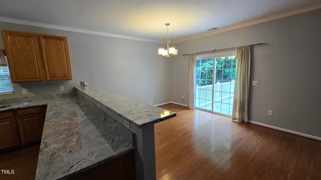 an empty room with wooden floor cabinet and windows