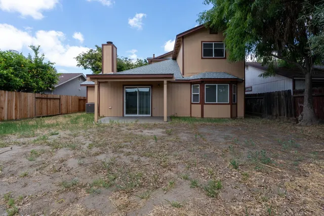 a view of a house with a yard and a large tree