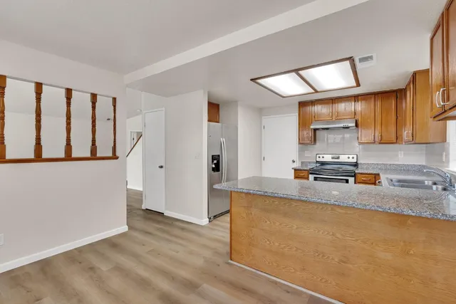 a kitchen with stainless steel appliances granite countertop a sink a stove and a refrigerator