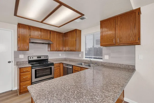 a kitchen with stainless steel appliances granite countertop wooden cabinets a oven and granite counter tops