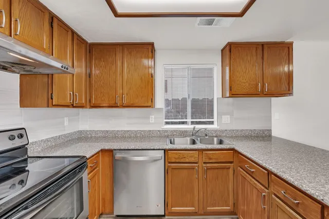 a kitchen with stainless steel appliances granite countertop a sink stove and cabinets