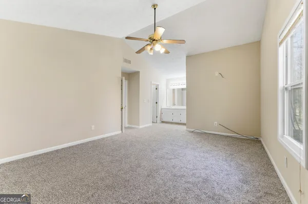 an empty room with windows and fan