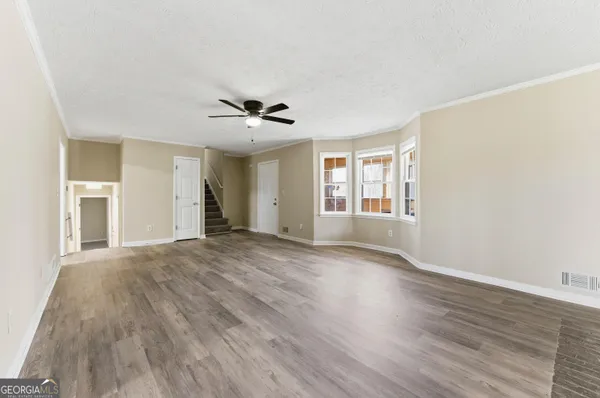 a view of an empty room with a window and wooden floor