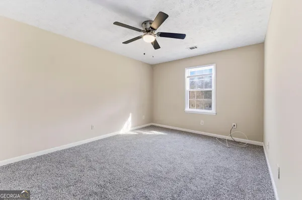an empty room with ceiling fan and windows