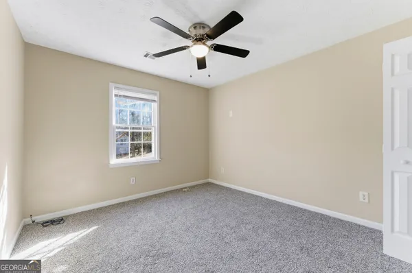 an empty room with windows and ceiling fan