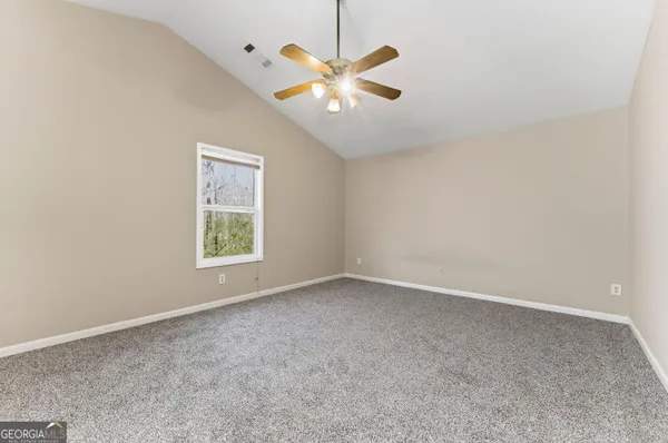 an empty room with ceiling fan and window