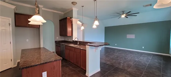 a kitchen with kitchen island granite countertop a stove a sink a refrigerator and a counter top space