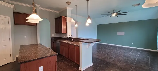 a kitchen with kitchen island granite countertop a stove a sink a refrigerator and a counter top space