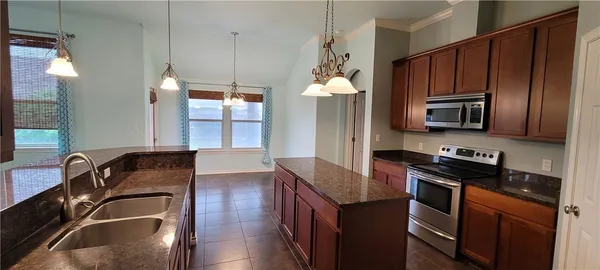 a kitchen with granite countertop stainless steel appliances a stove a sink and a microwave