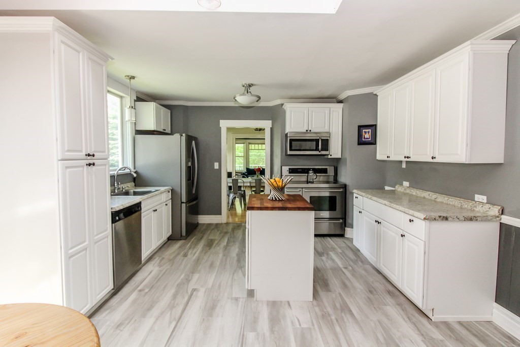 105 Bailey Road Holden, MA 01520 - Photo 8 of 42 a kitchen with granite countertop a refrigerator oven a sink dishwasher and white cabinets with wooden floor