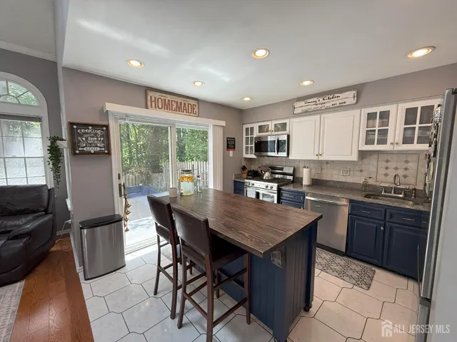 a kitchen with stainless steel appliances granite countertop a stove top oven a sink dishwasher a dining table and chairs with wooden floor