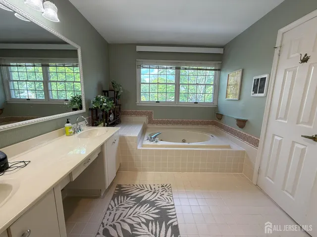 a spacious bathroom with a tub sink and mirror