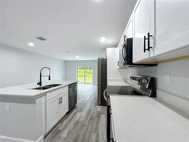 a kitchen with stainless steel appliances a sink a stove and cabinets