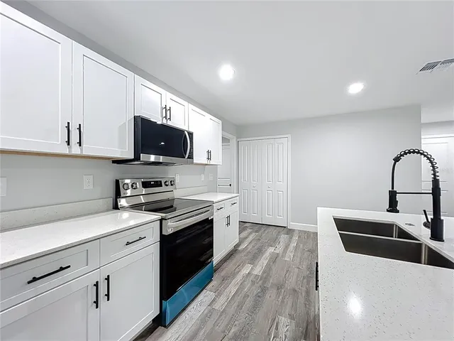 a kitchen with stainless steel appliances granite countertop a stove a sink and a microwave