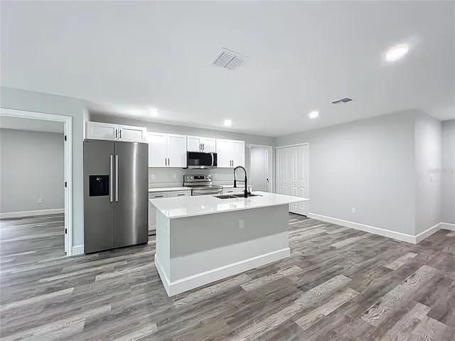 a kitchen with stainless steel appliances a stove top oven a refrigerator and a sink