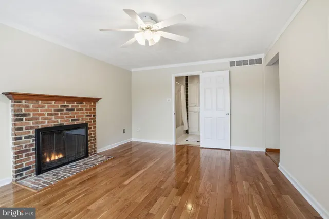 a view of an empty room with wooden floor fireplace and a window