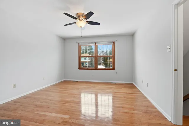 an empty room with windows and ceiling fan