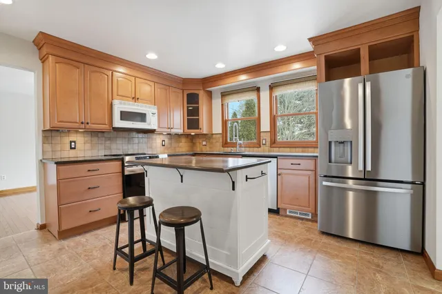 a kitchen with stainless steel appliances granite countertop a refrigerator a stove a sink and a microwave