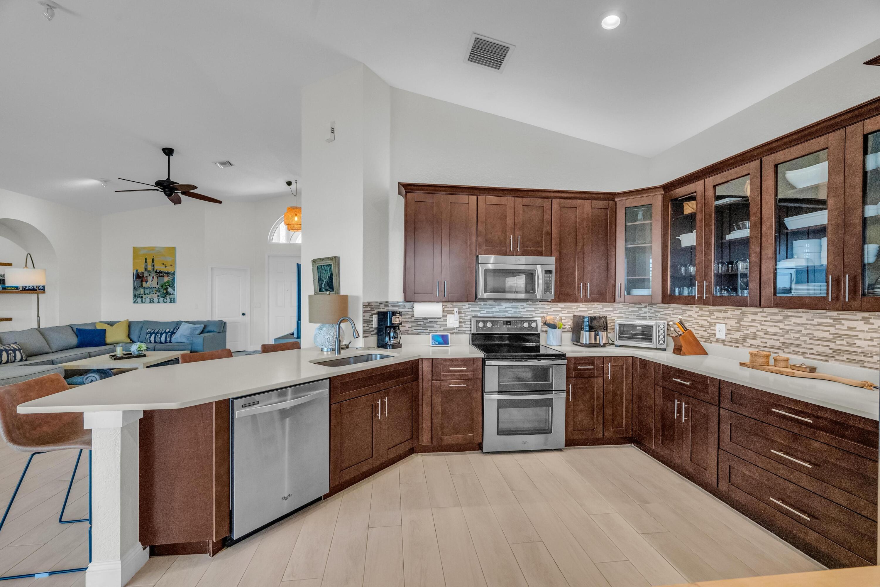 5902 Walnut Park Lane Fort Pierce, FL 34951 - Photo 15 of 45 a kitchen with stainless steel appliances granite countertop a stove top oven a sink dishwasher a dining table and chairs with wooden floor