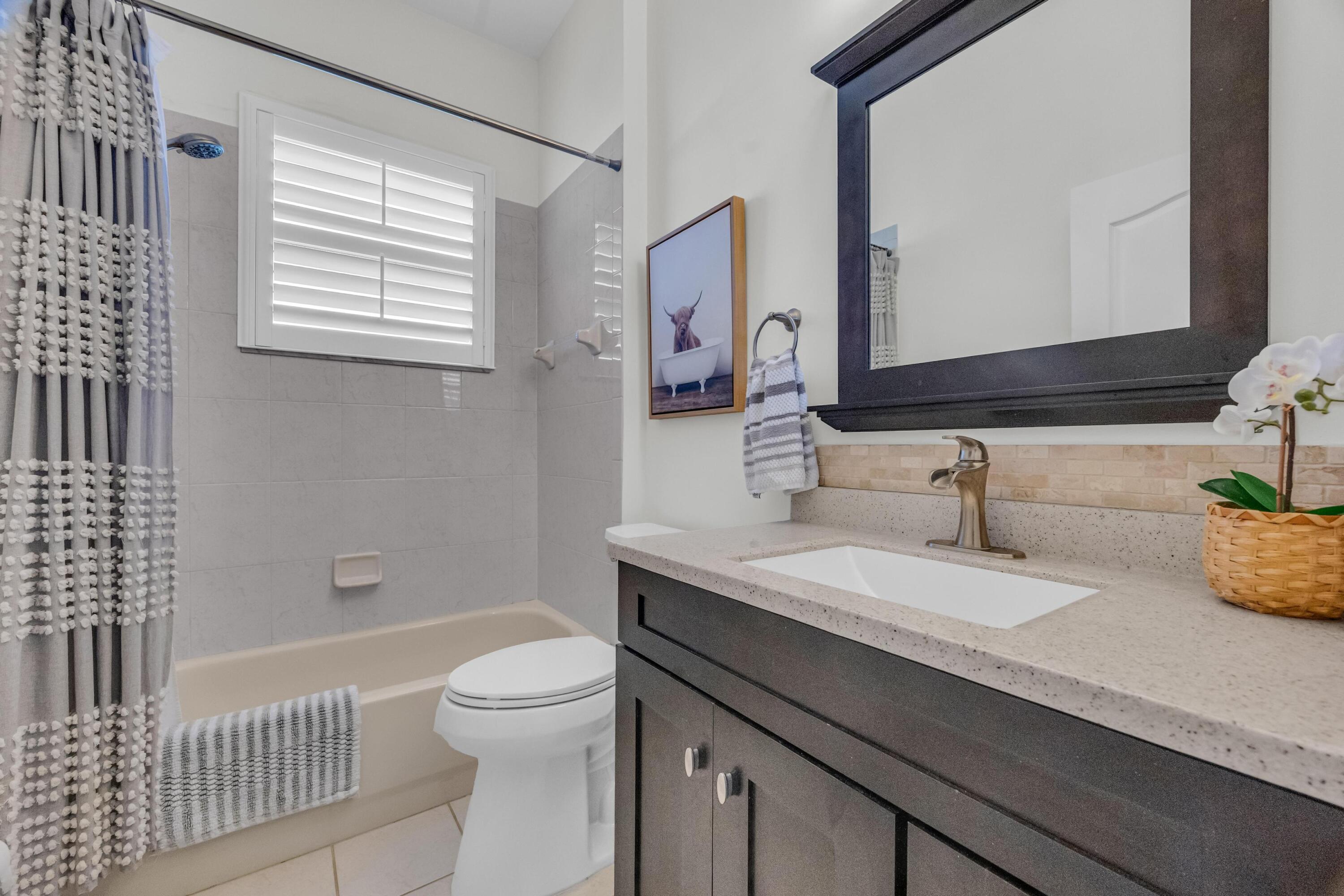 5902 Walnut Park Lane Fort Pierce, FL 34951 - Photo 26 of 45 a bathroom with a granite countertop sink a toilet a mirror and shower