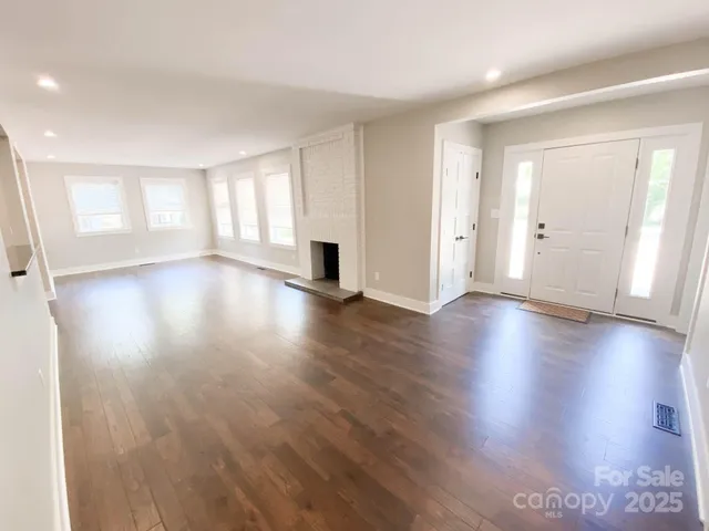 a view of an empty room with wooden floor and window