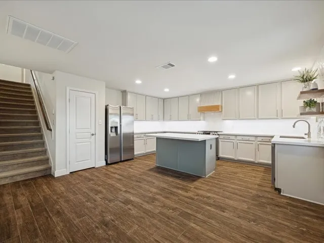 a large white kitchen with wooden floors stainless steel appliances