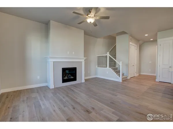 a view of an empty room with wooden floor fireplace and a window